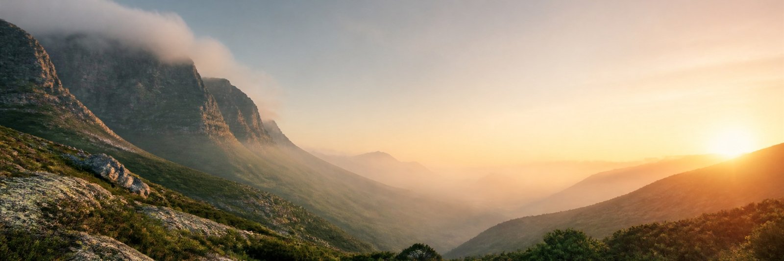 Sunrise breaking over a mist-filled mountain valley between rocky peaks